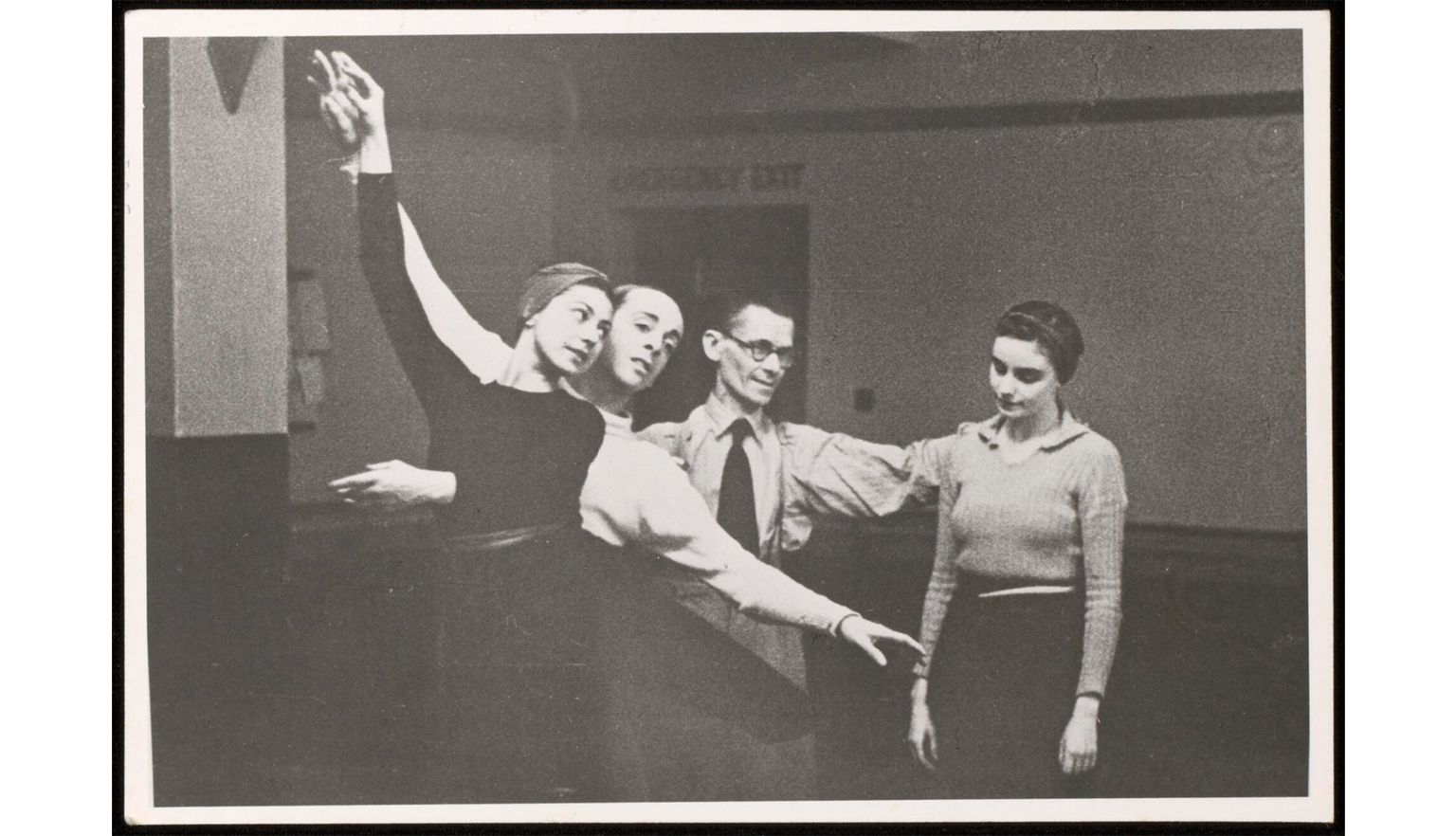 A man and woman hold a ballet pose while a second man has his hand on the shoulders of a second woman who is looking down