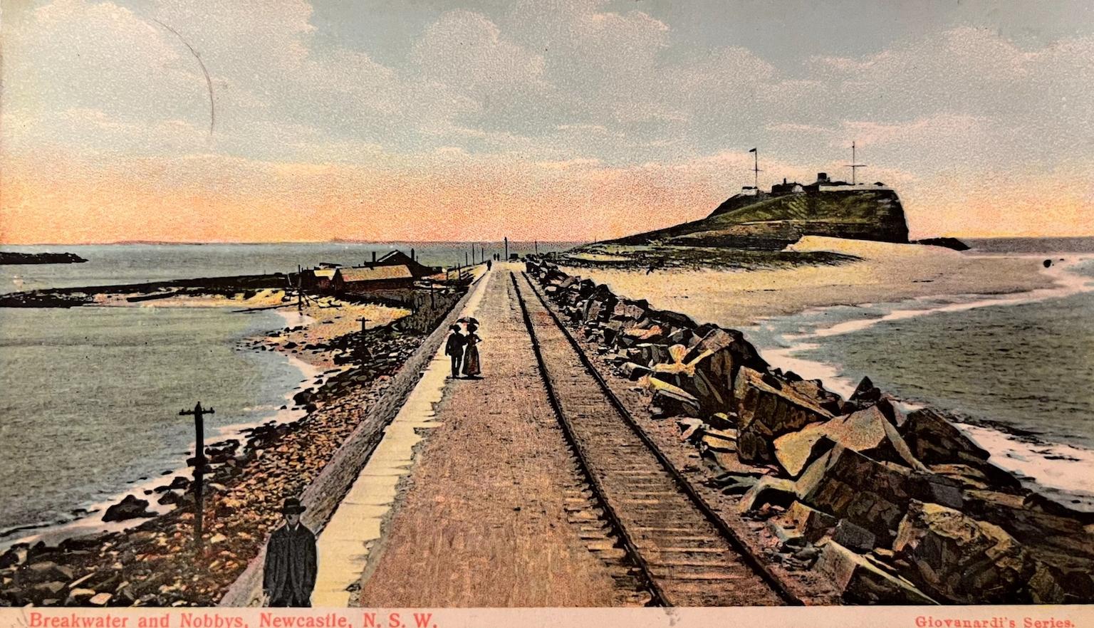 Front of an old postcard with an image of a couple walking along a pier extending into the sea