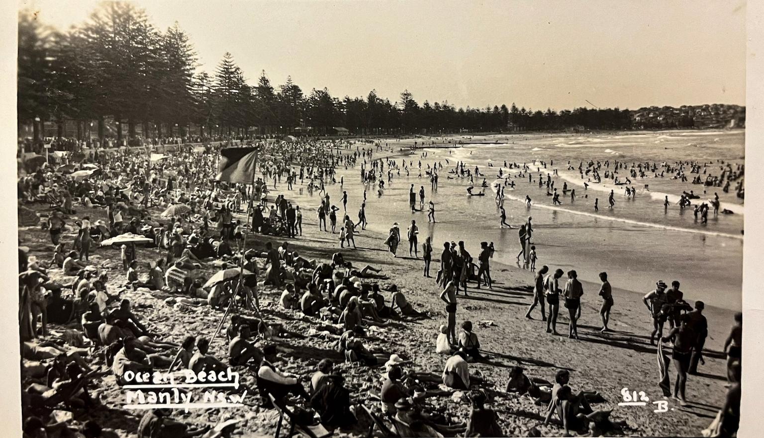 Front of an old postcard with a black and white photo of crowds at Ocean Beach in Manly