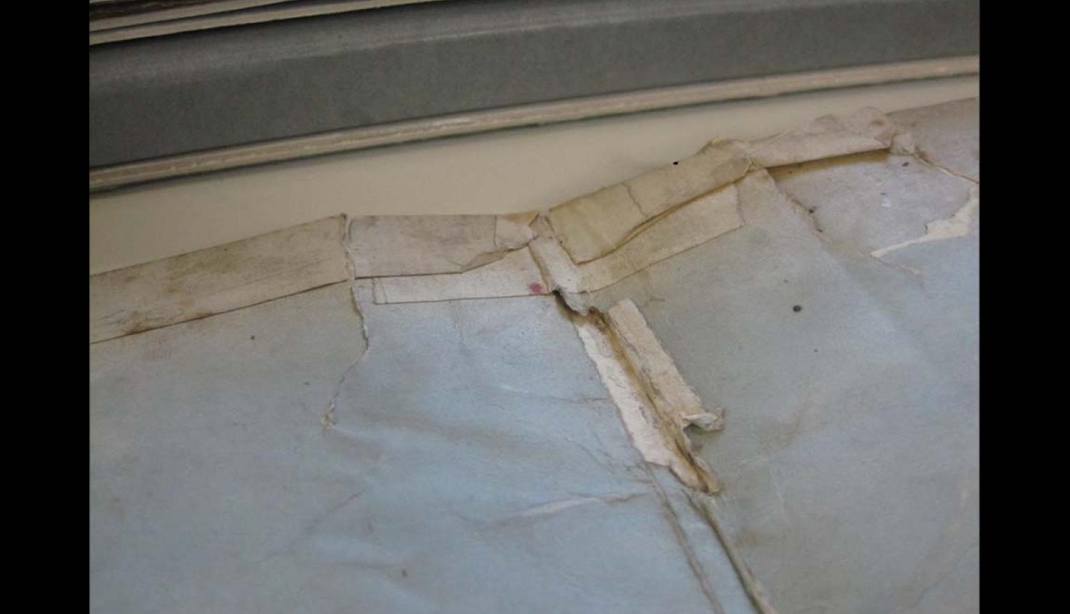 The spine and edge of an open old book patched together with cloth