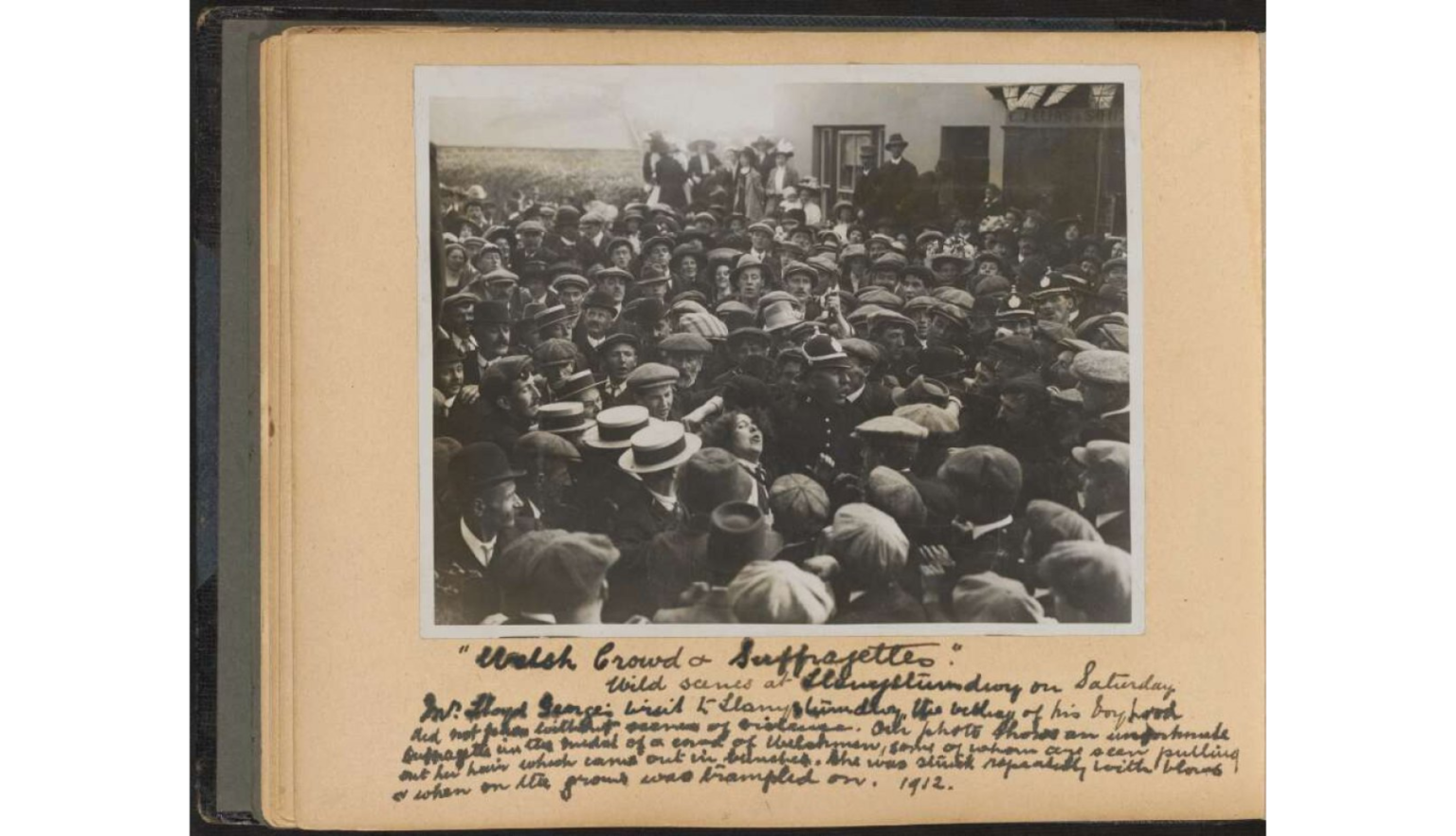 A densely packed crowd of men and women outdoors, with one woman being pulled by her hair.