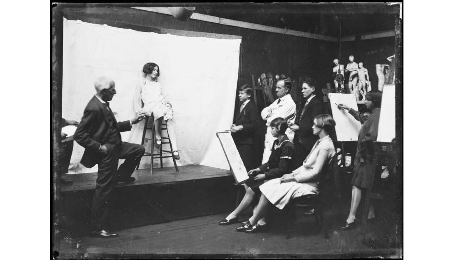 black and white photograph of a group of young women drawing a model