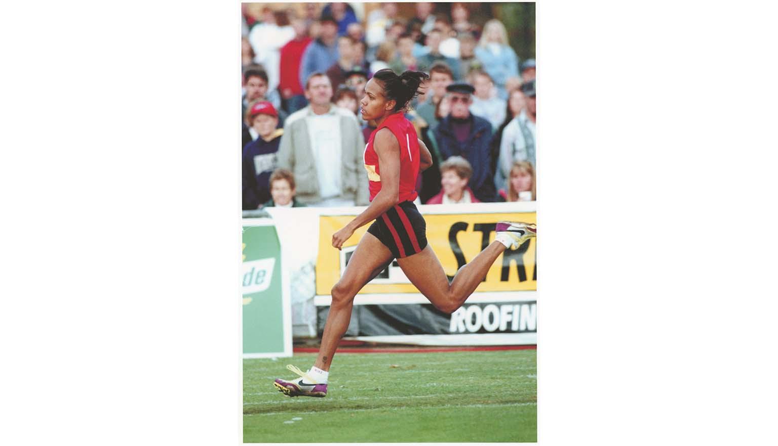Photo of Cathy Freeman running in front of a crowd at a sport stadium