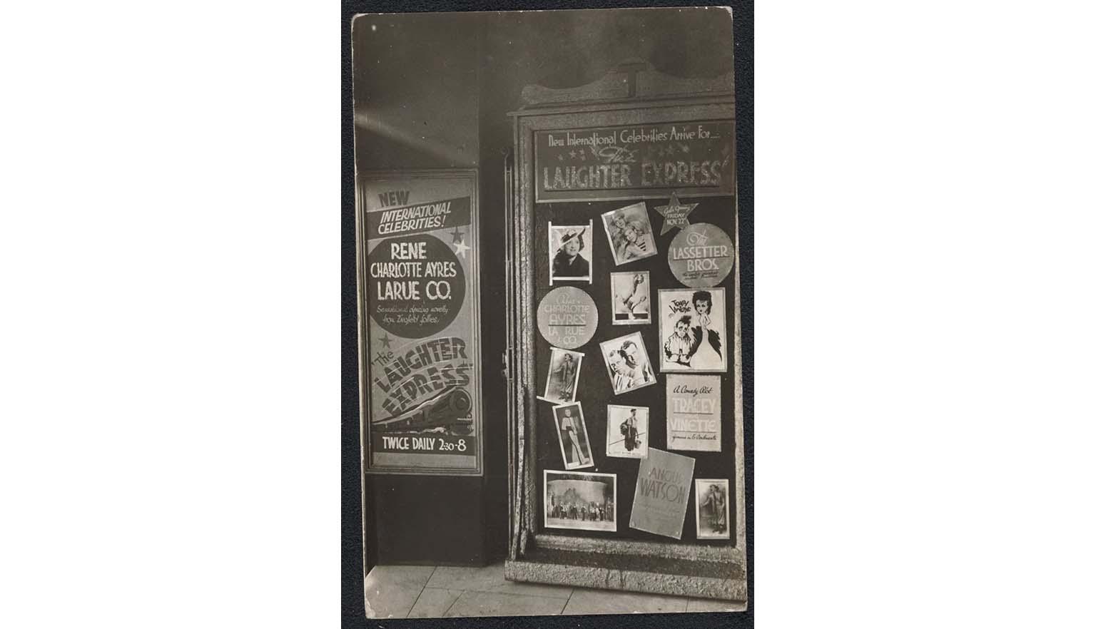 A black and white photograph of a series of billboards advertising vaudeville performances and the stars in them. One poster, for the Laughter Express, shows a steam train and the names of the performers, including Roy Rene