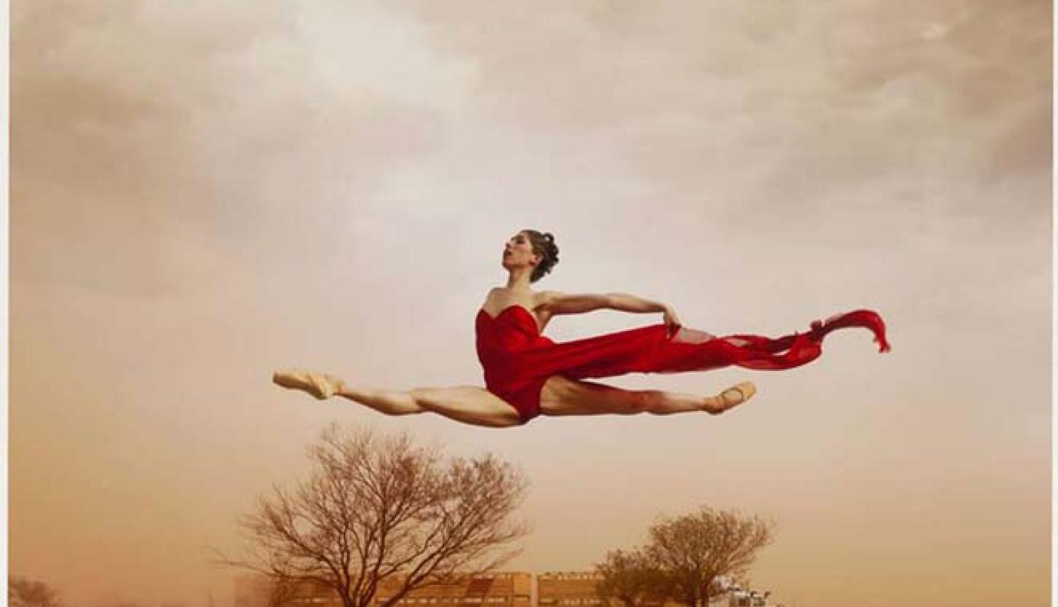 A dancer leaping in the air with red desert around her