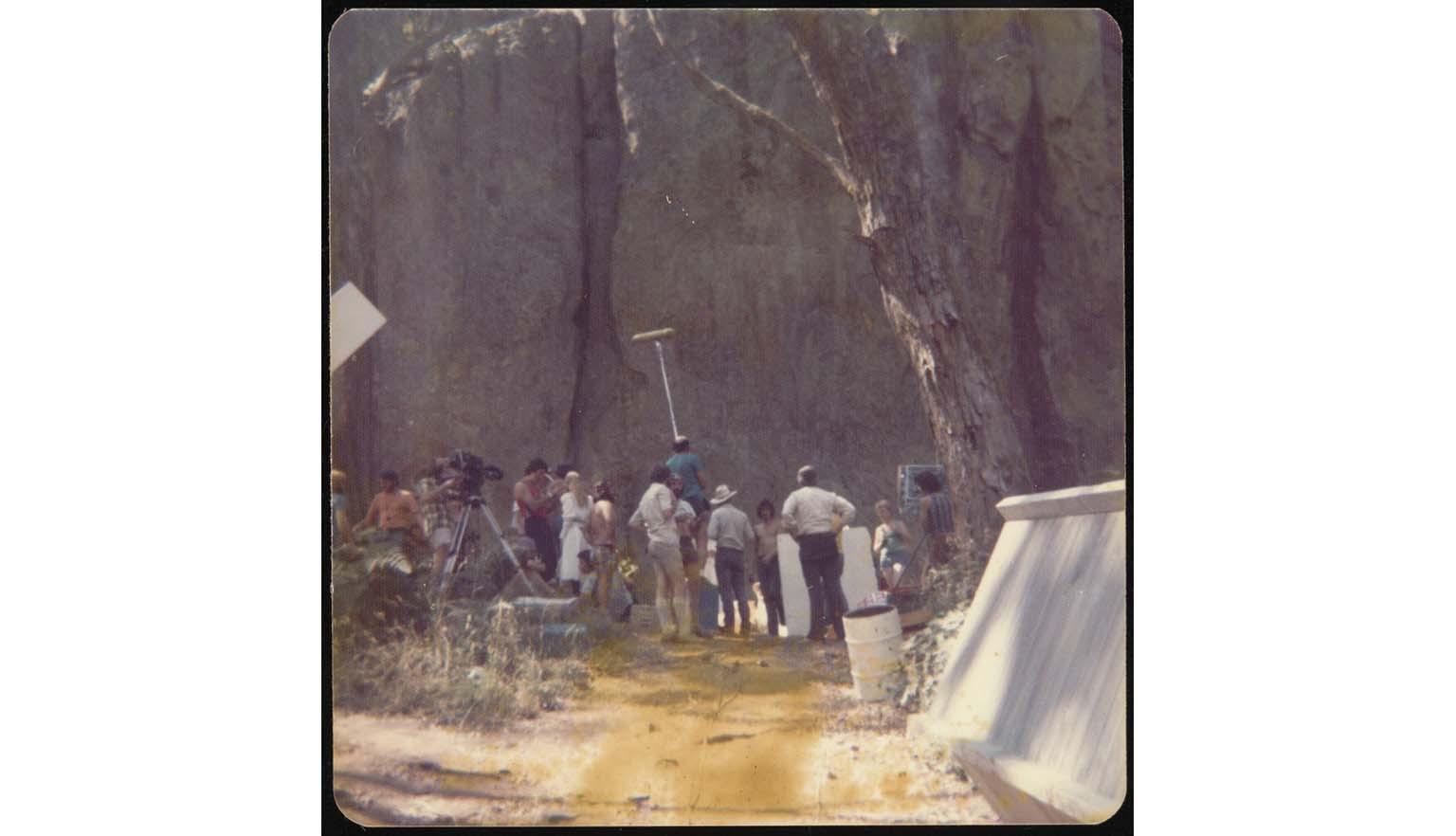 A group of people filming at base of Hanging Rock from a distance