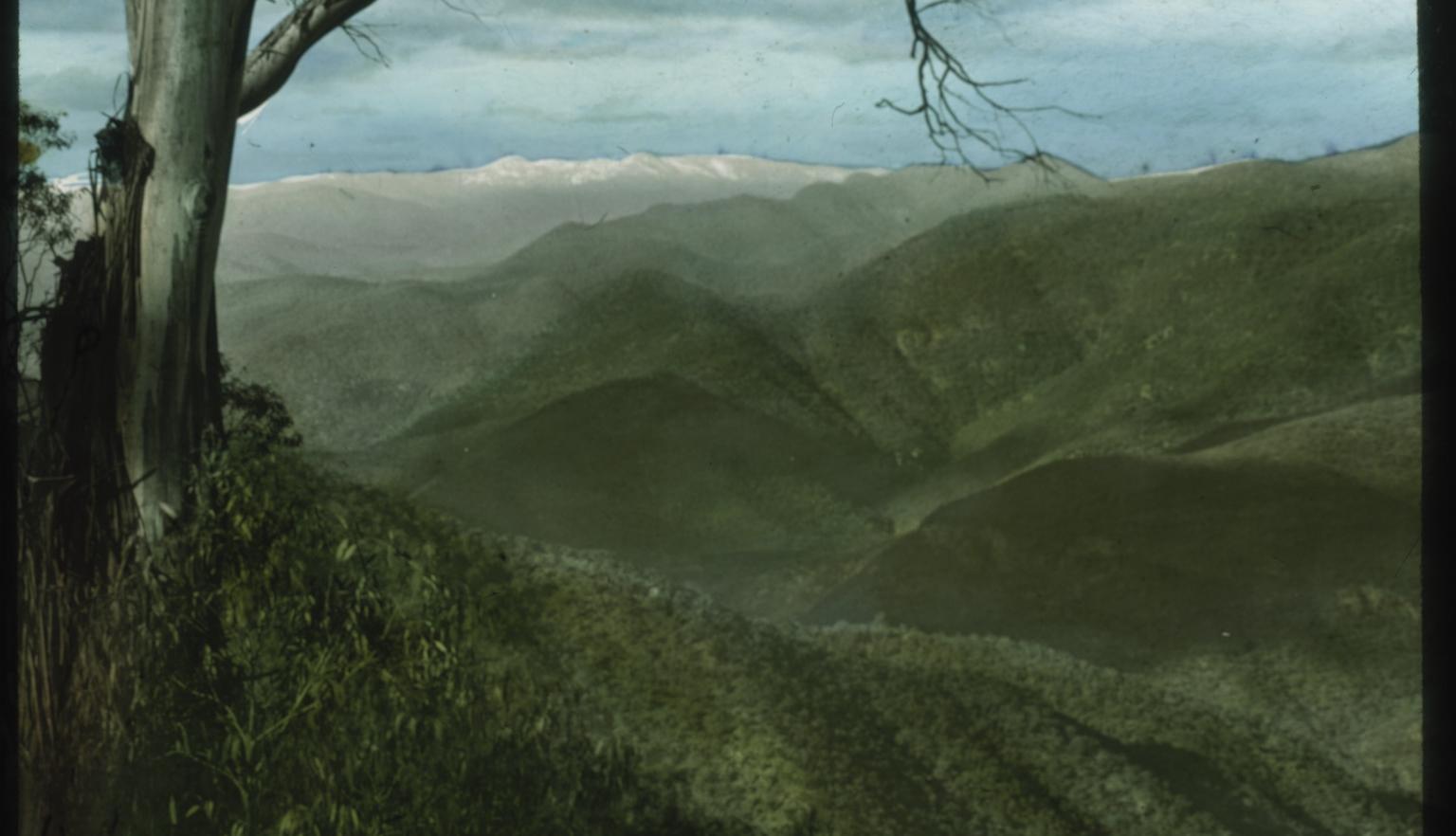 View from the top of a mountain at the valley below and maountain range extending towards the distance