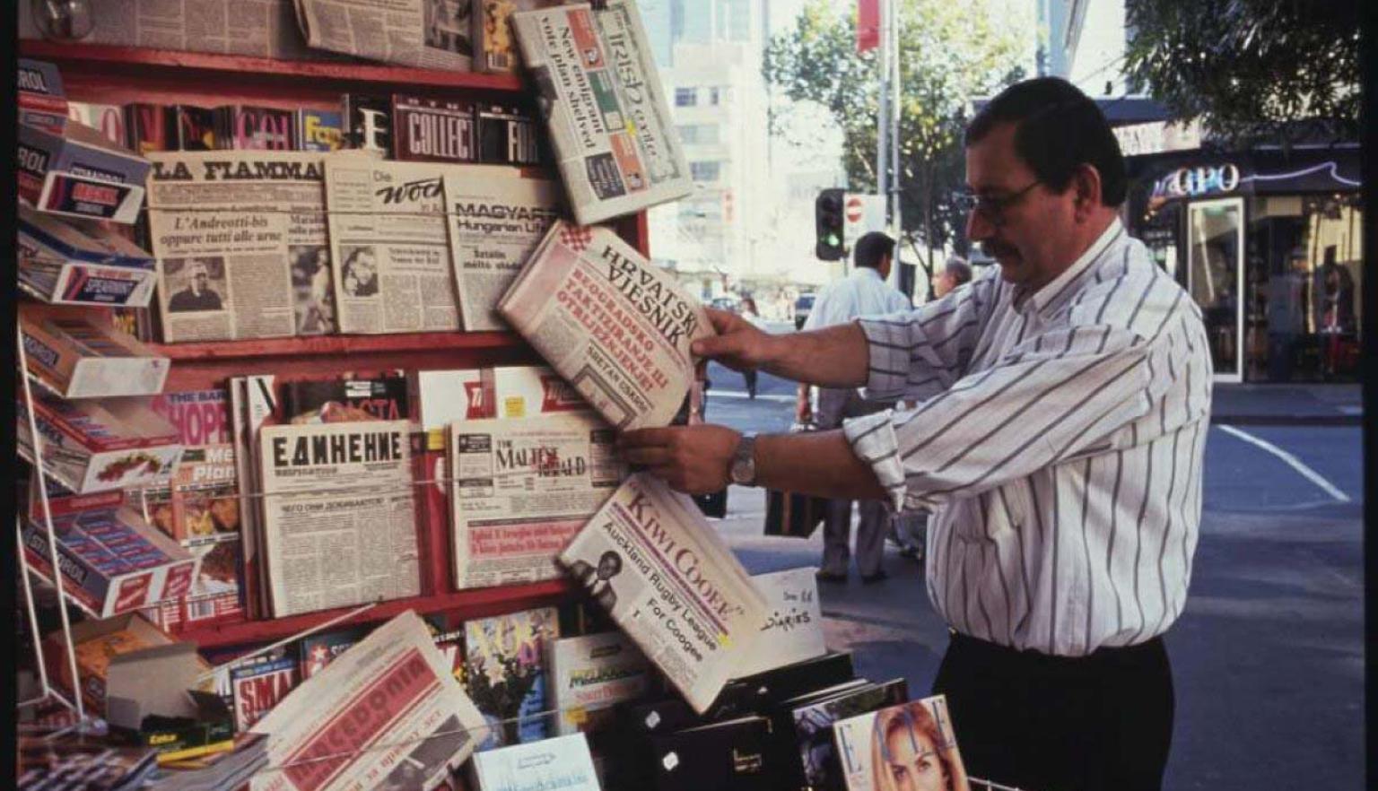 A man looking at newspapers in multiple languages at a newspaper kiosk on Elizabeth Street, Melbourne.
