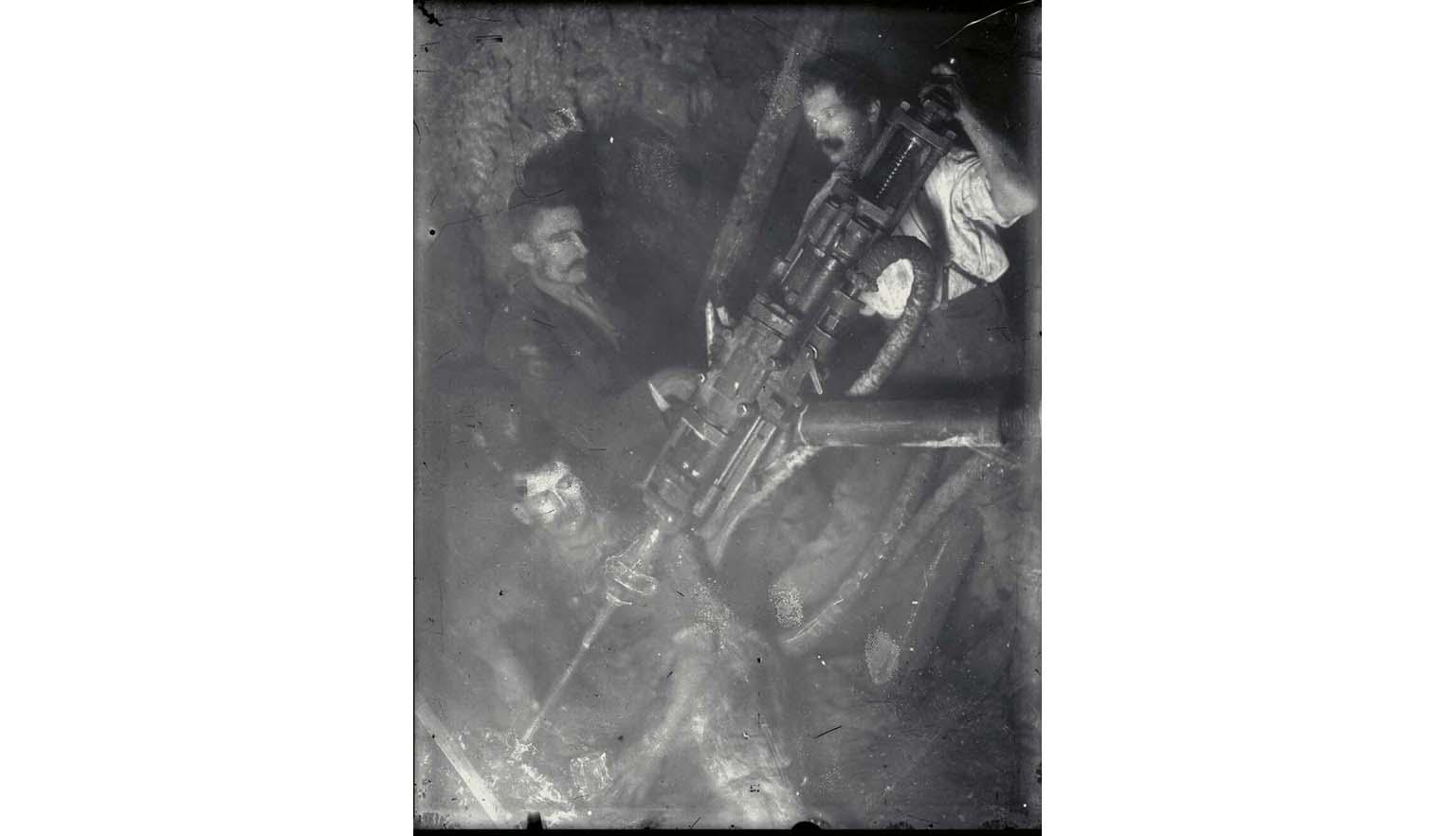 black and white photograph of three miners with early pneumatic hammer drill