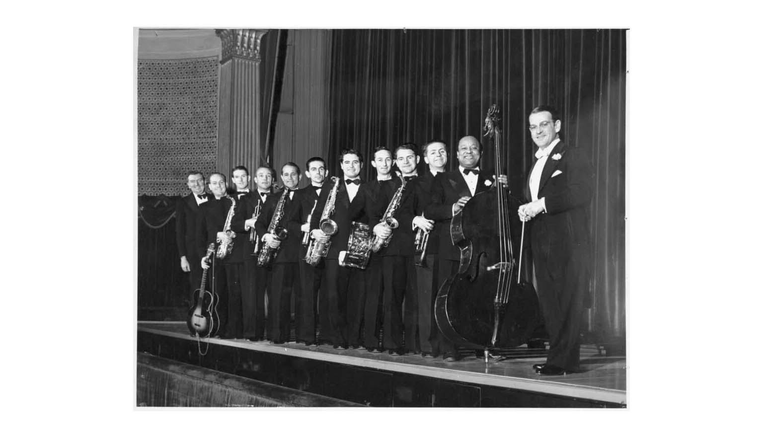 A row of men in concert dress holding musical instruments
