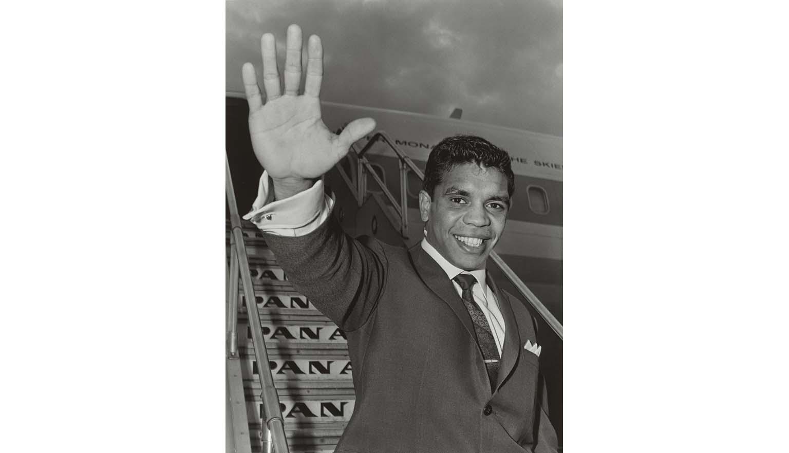 Black and white photo of Lionel Rose waving from the steps of a Pan Am plane in 1968