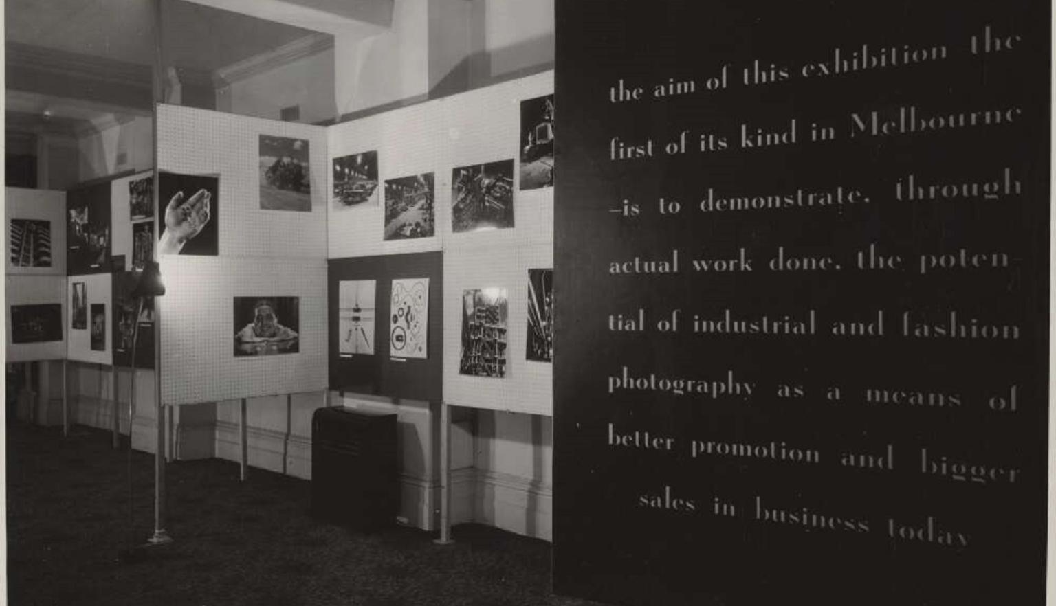 Black and white photograph of an exhibition display featuring various photographs mounted on white panels. The exhibit showcases examples of Wolfgang Sievers industrial and fashion photography.
