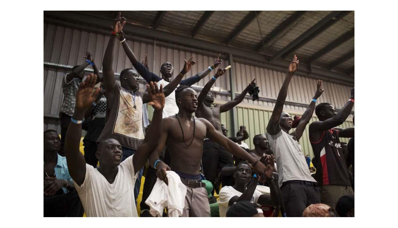Photo of Australian South Sudanese men watching and cheering 