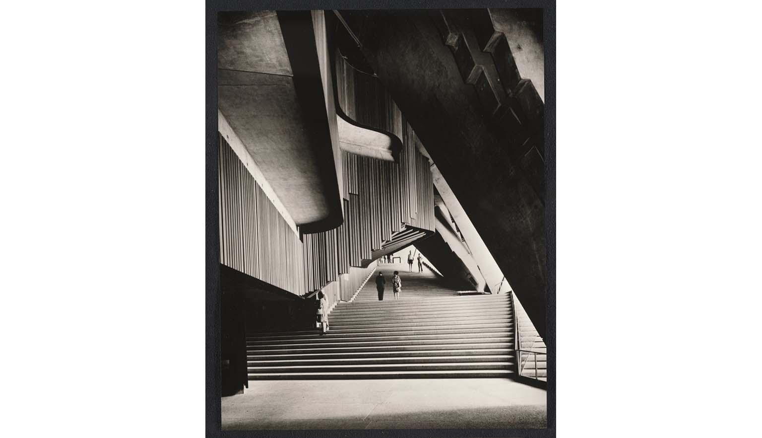 A sepia photograph of the interior of the Sydney Opera House. The architecture is a series of geometric patterns at opposing angles and directions.