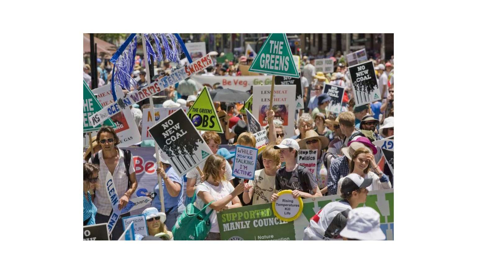 Photo of a large crowd with placards against global warming.