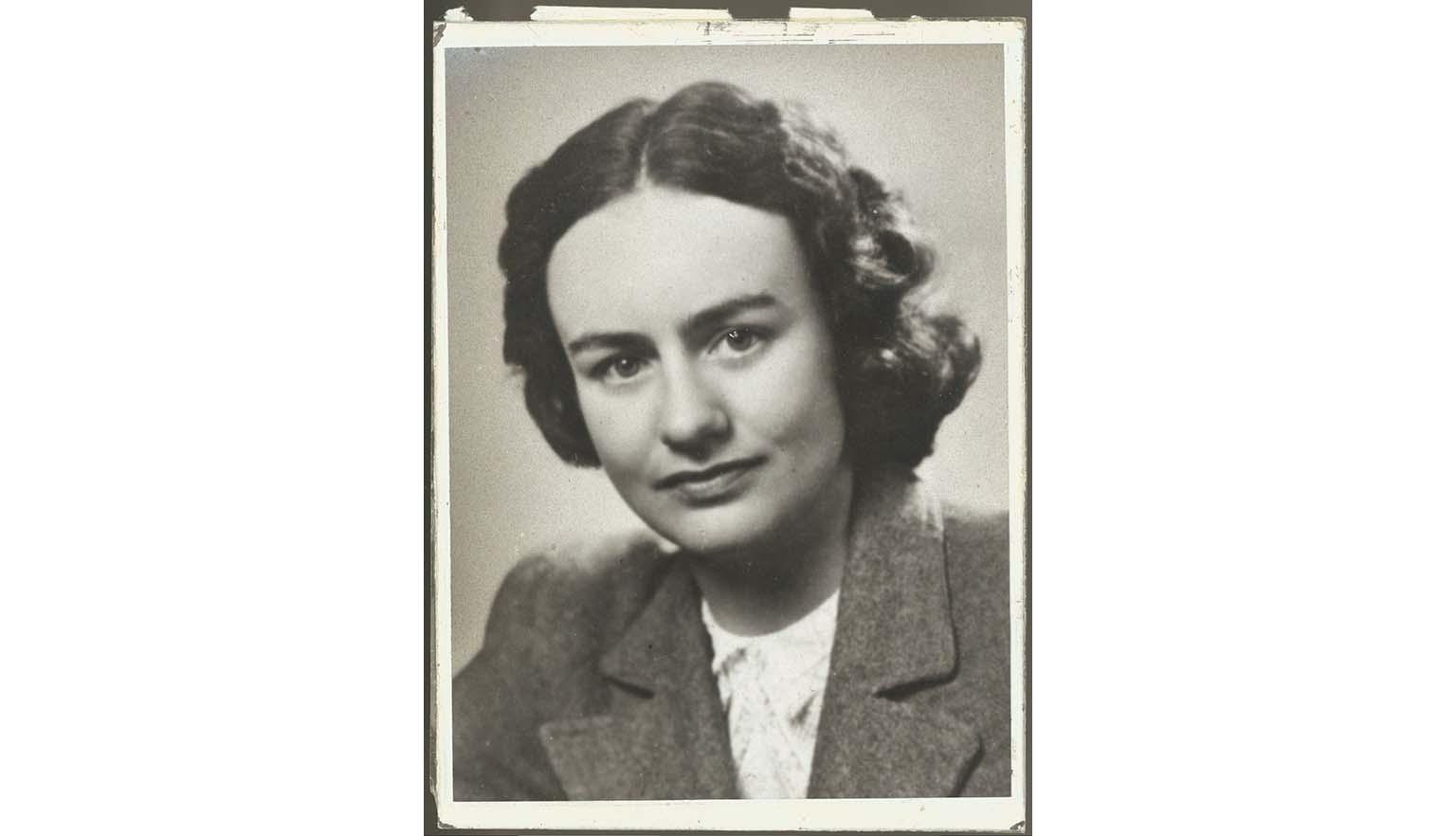 A black and white portrait photo of a young woman with brown hair in a 1940's hairstyle, wearing a wool suit jacket over a white lace shirt.