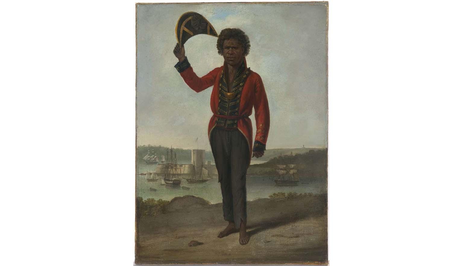 A portrait of a man. He has dark skin and hair. He is an Australian Indigenous man and is wearing a European style officers coat and trousers. His trousers are tattered at the cuffs. He is holding a tricorn hat in the air. In the background sailing ships can be see on the harbour. A large fort can be seen on a spit of land.