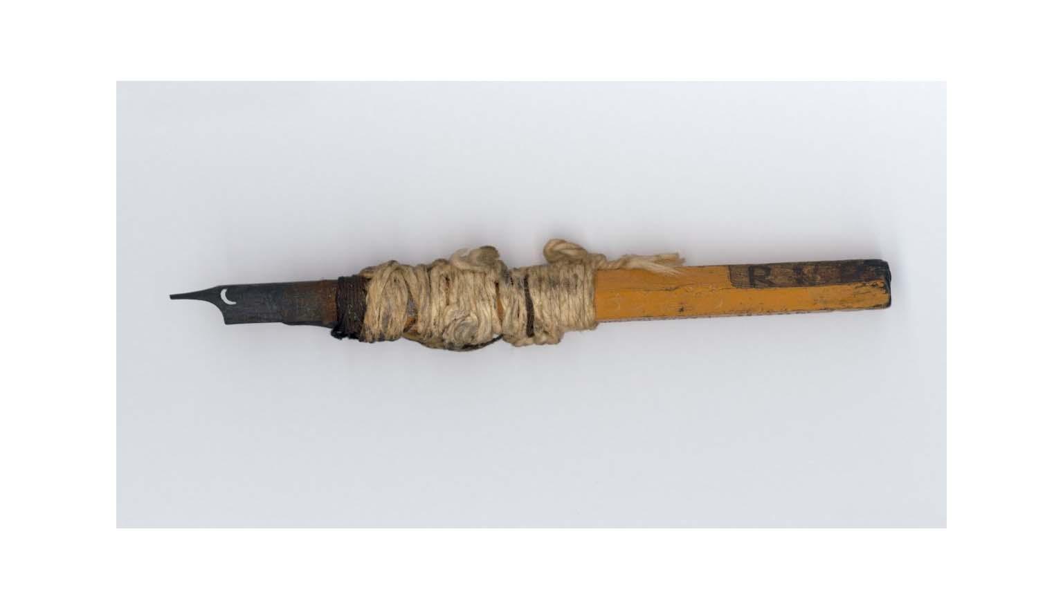 A steel pen nib stuck in the end of a pencil and wrapped in string to bind them.