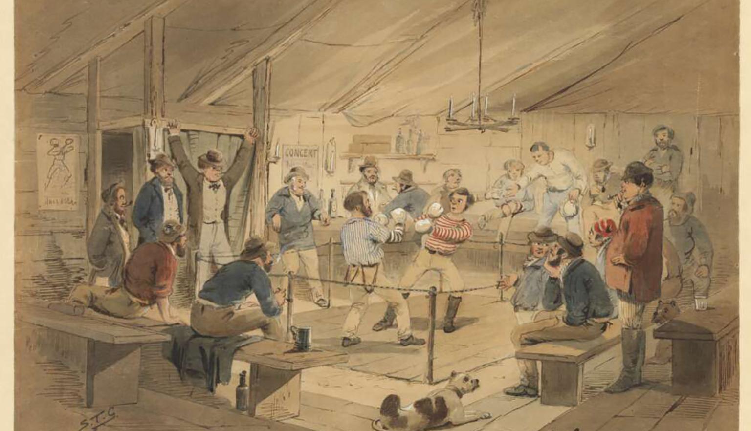 A group of approximately 20 men cheering and drinking whilst watching a boxing match. One boxer is in a blue shirt and one in a red shirt. A dog is in the foreground laying on the floor. 