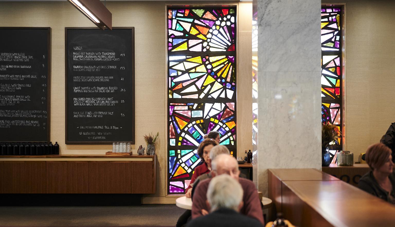 Visitors of bookplate, the menu chalkboards and stained-glass windows in the background