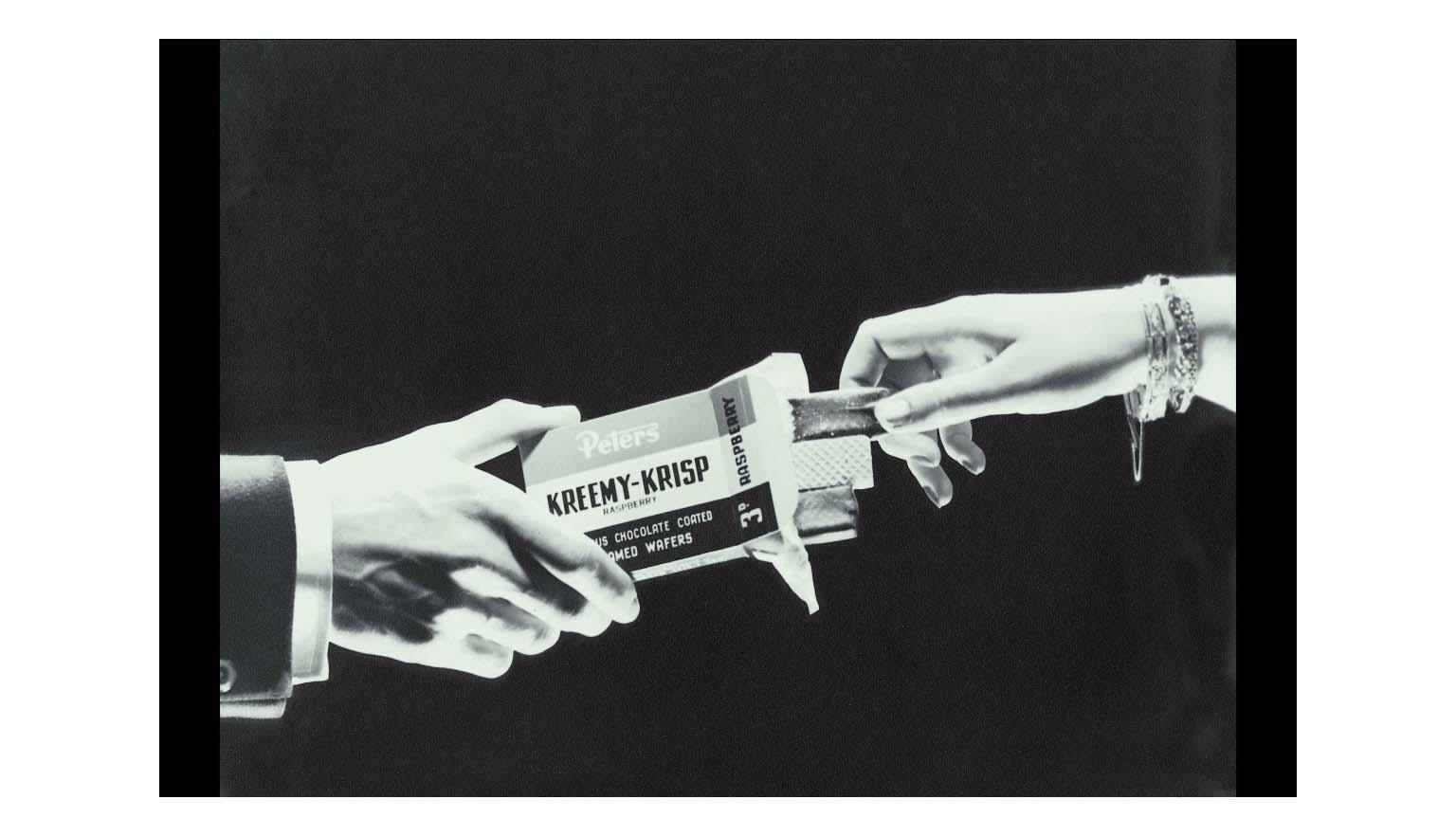 black and white photo of woman's hand removing wafer from a box offered by a man's hand