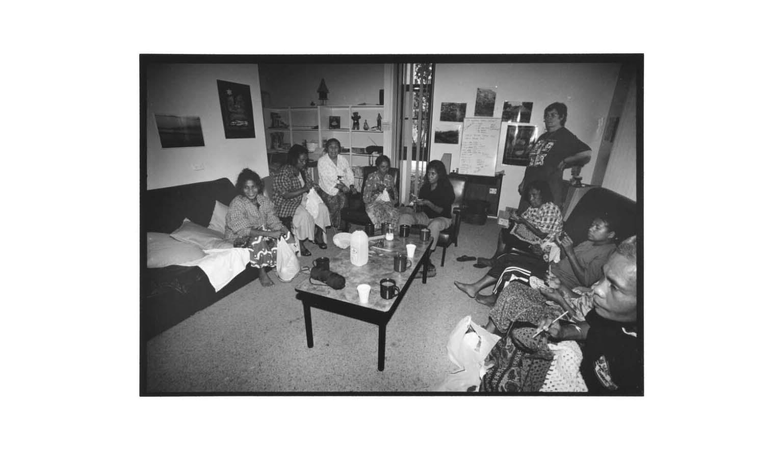 Group of men and women from East Timor sitting on couches around a coffee table crocheting