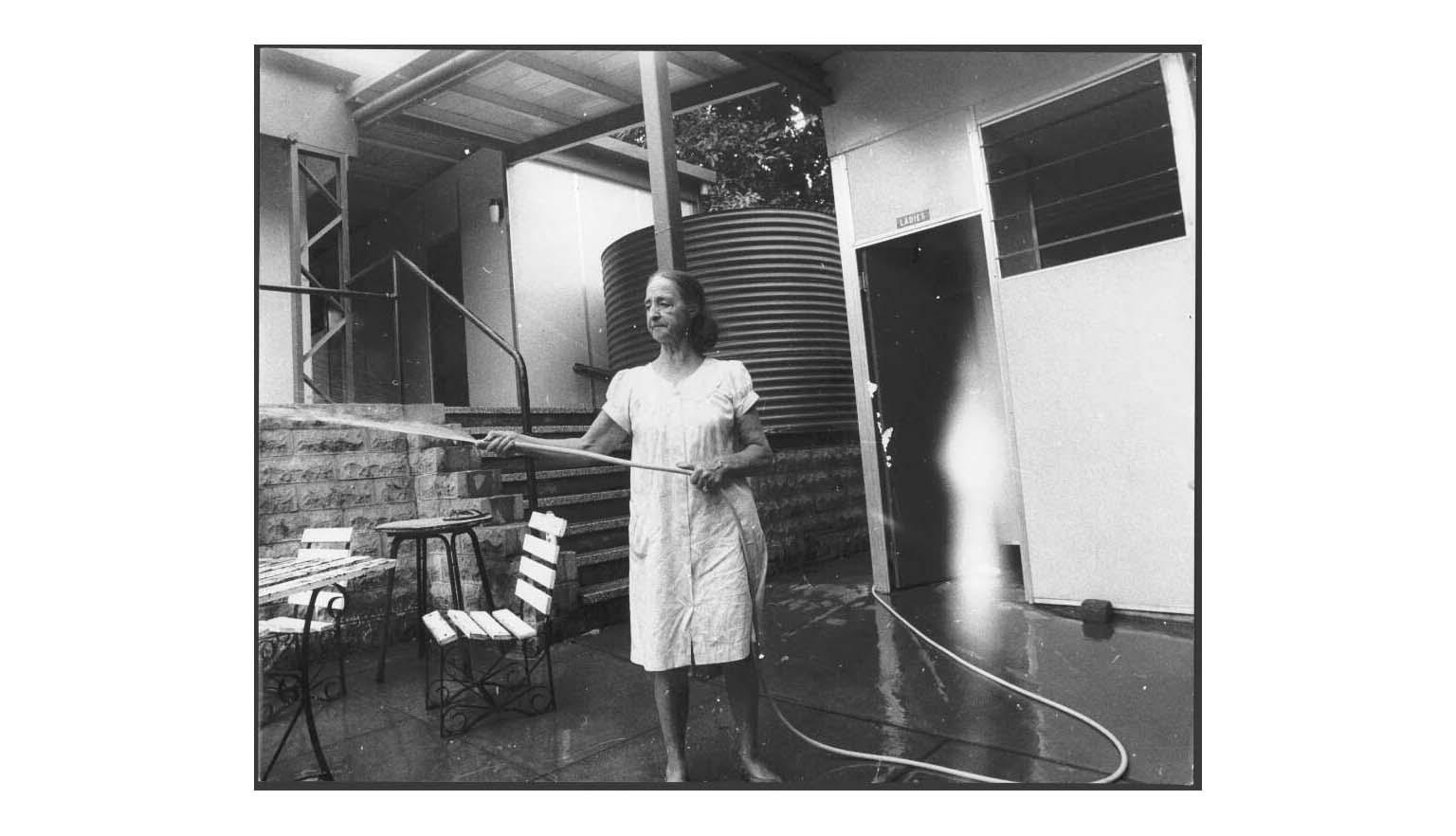 black and white photo of a woman hosing down a beer garden