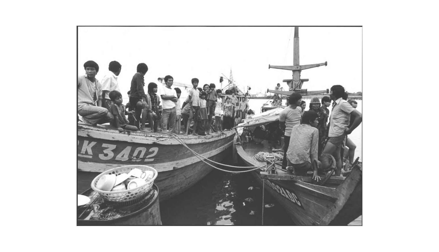 Two boats with rope hanging between them filled with men, women and children coming from Vietnam