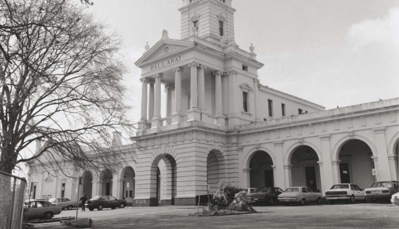 Black and white photo of the Ballarat Railway Station with cars parked outside it
