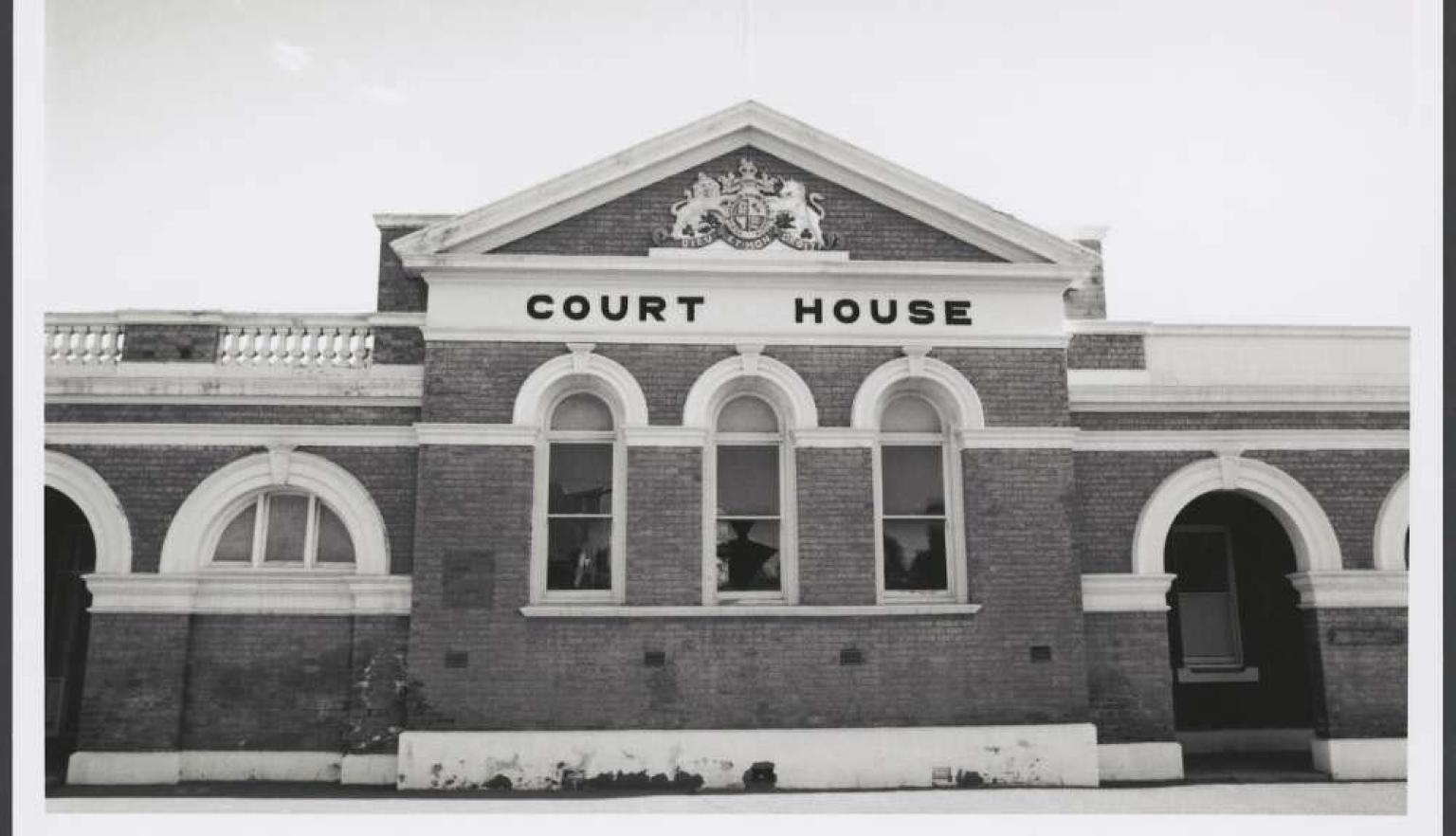 Black and white photo of a brick building with a crest and the words 'Court House' at the top
