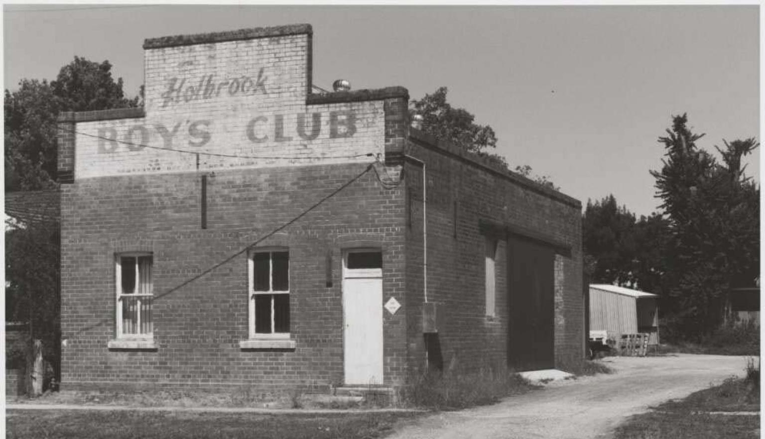 Black and white photo of a brick building with a faded sign saying 'Holbrook Boys Club'