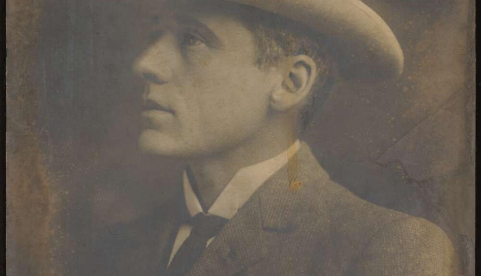 A photograph of Australian poet Banjo Paterson in side profile. He wears a hat and a suit jacket.