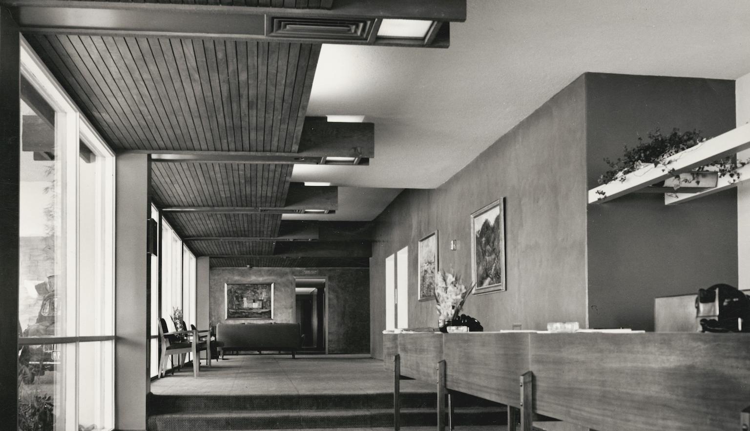 Black and white photo of the reception area of a hotel, with wooden features