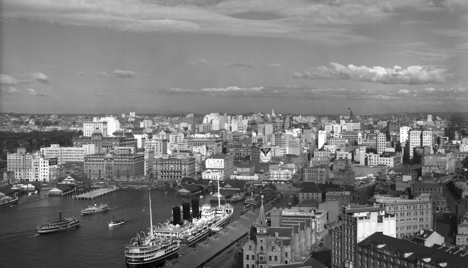 A view of Circular Quay in the 1940s taken from a Bridge Pylon. A ship in the foreground, with low-rise multi-story buildings in the background.