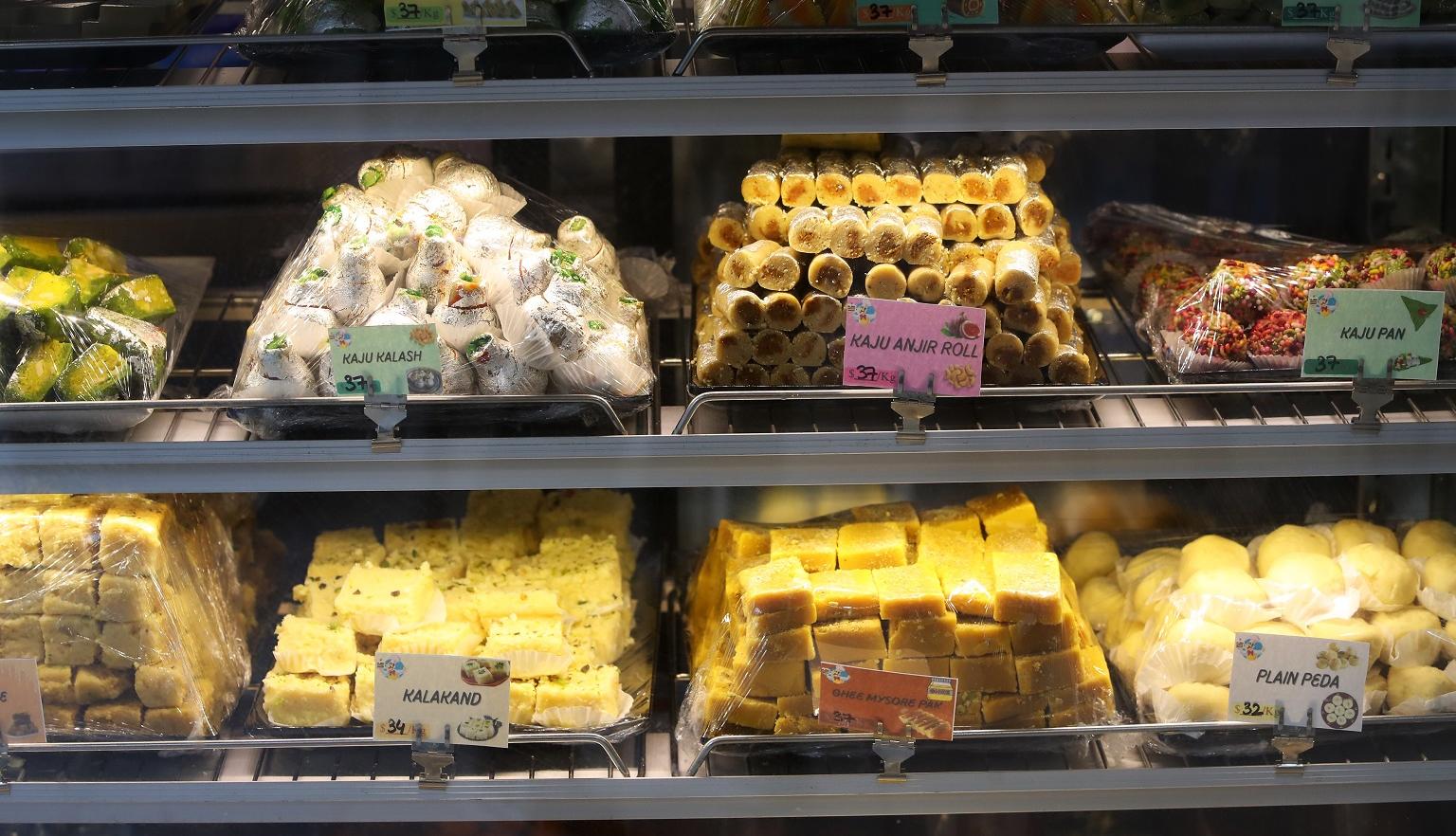 Small piles of traditional Indian sweets in a glass display case