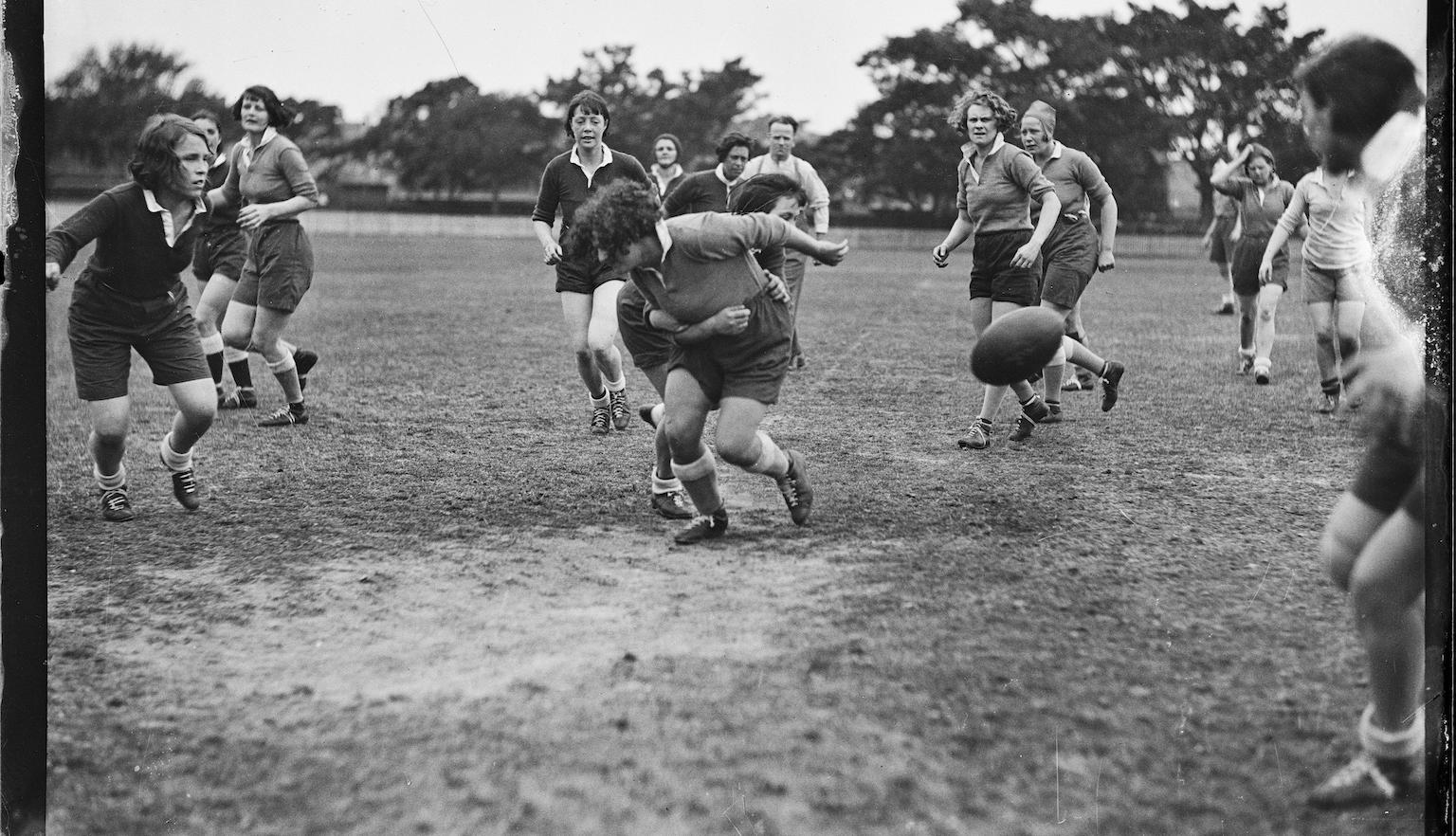 Black and white photo of women playing football in the park