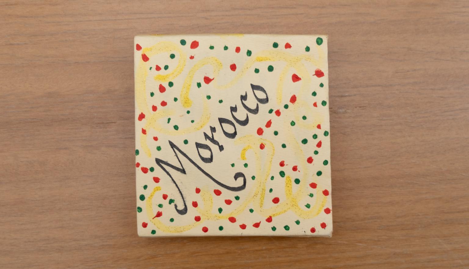 Yellow slipcase with black text reading 'Morocco', yellow swirls and red and green dots