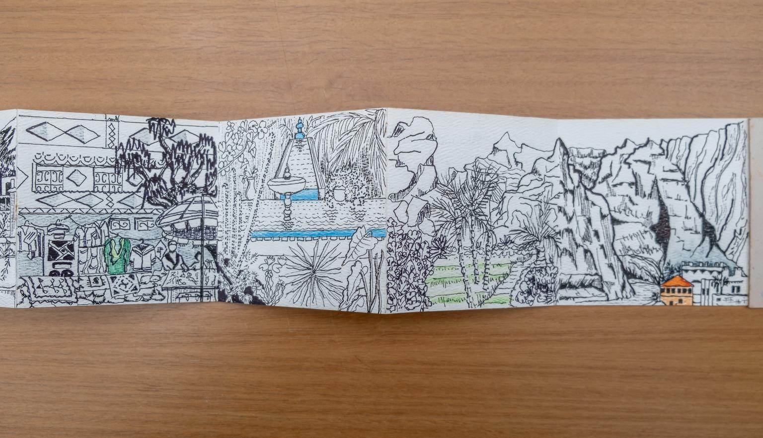 Fold-out travel diary open to three pages with black and white illustrations of Morocco gardens, houses and landscapes