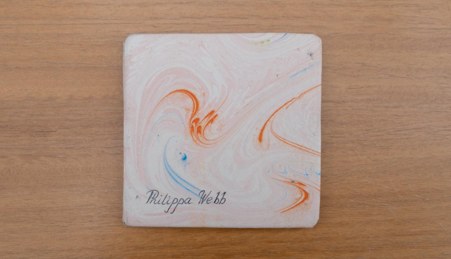 Travel diary back cover with an orange, white and blue swirl design and the name 'Philippa Webb' written on the lower left corner