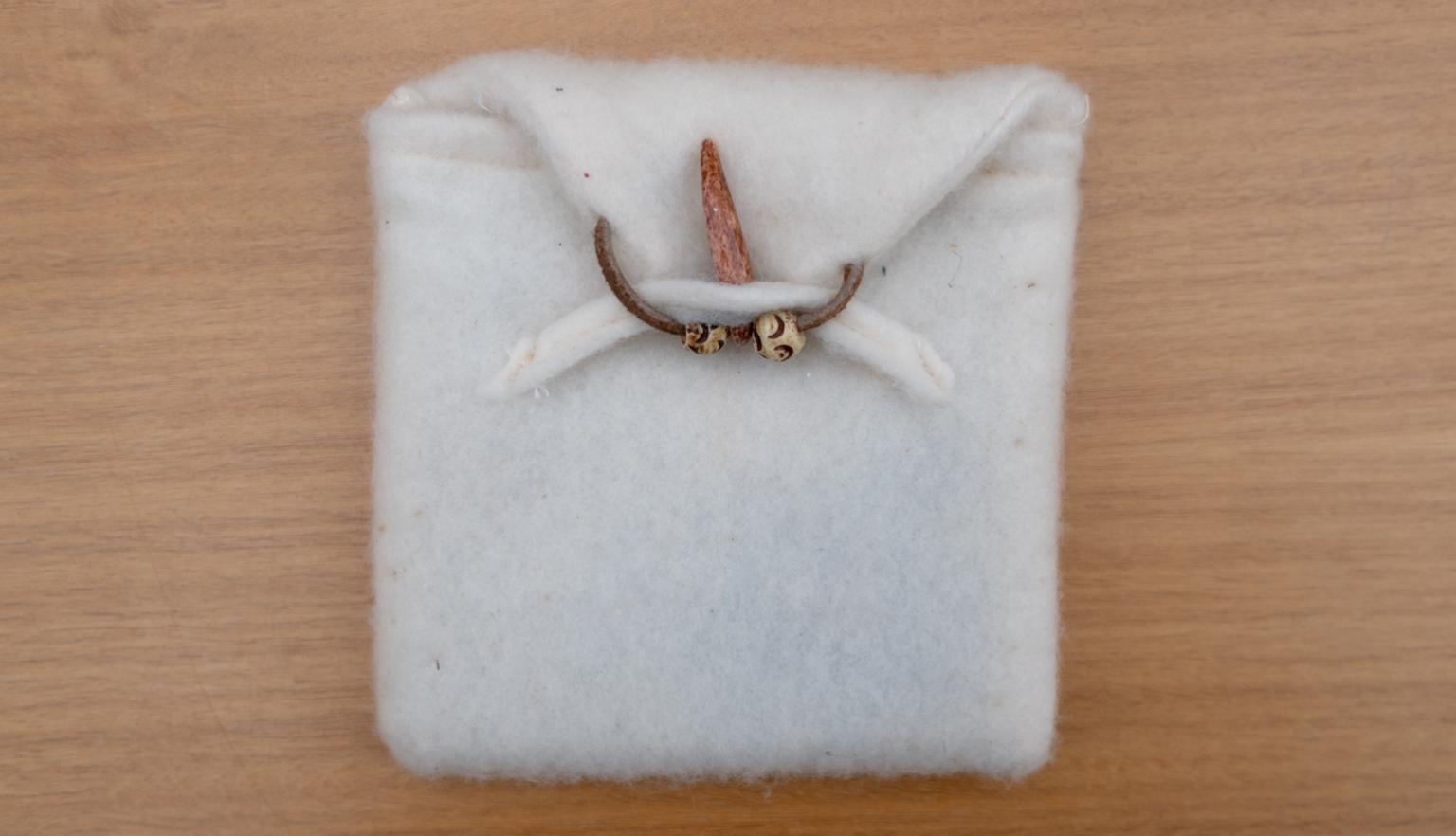 Fluffy white fabric pouch held closed with a wooden bead