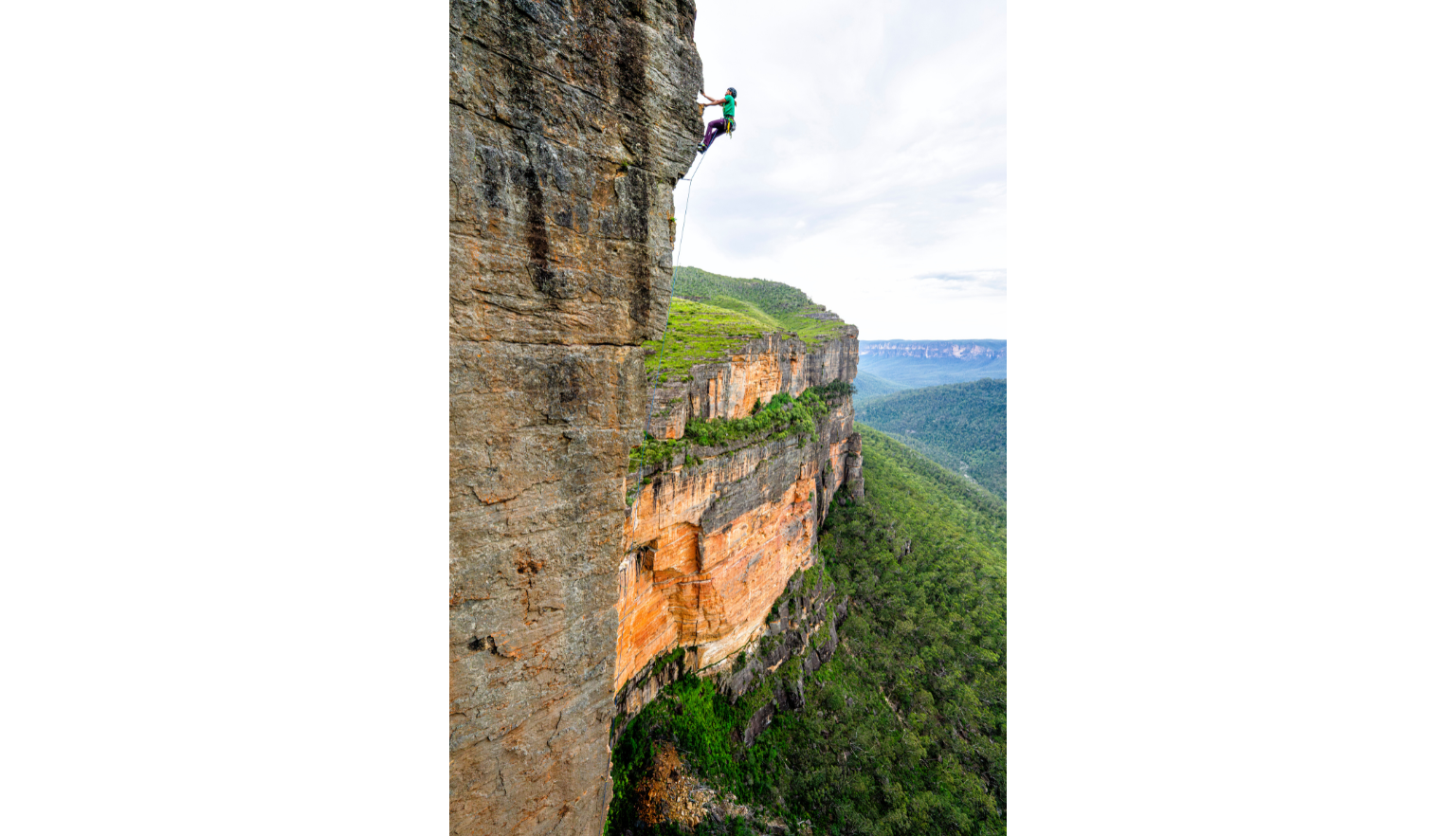 Female mountain climber descending a steep cliffside