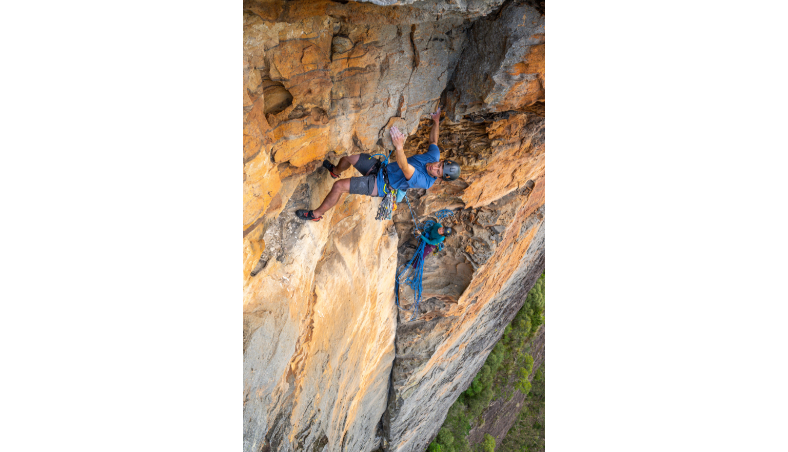 Two mountain climbers moving along a very steep cliff side