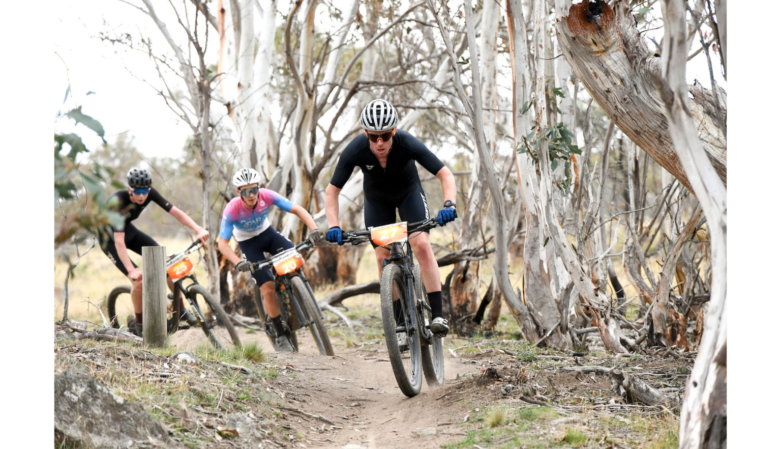 Three mountain bikers racing through a dirt track