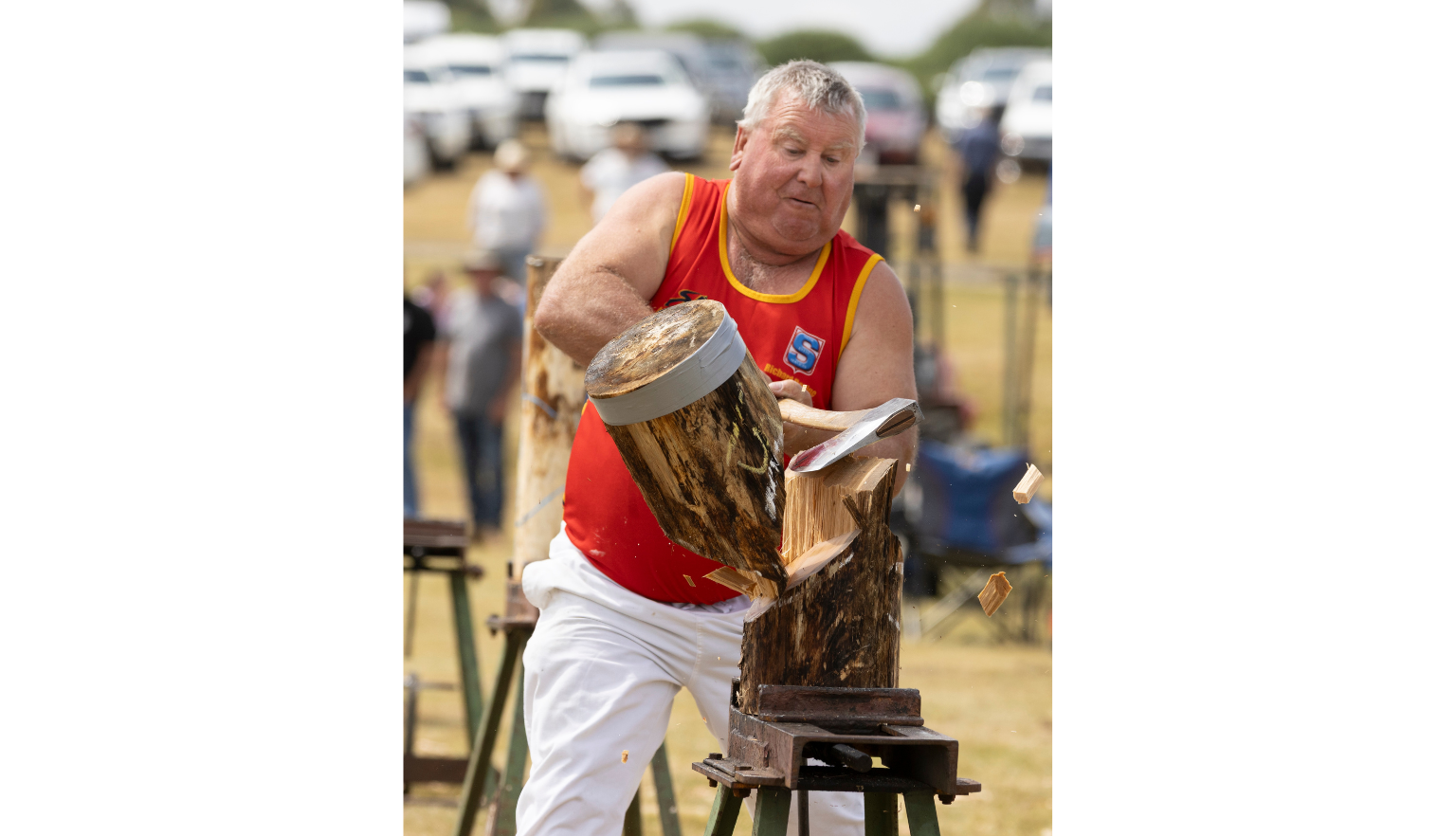 Man in a red shirt chopping an upright blog of wood in halk with an axe
