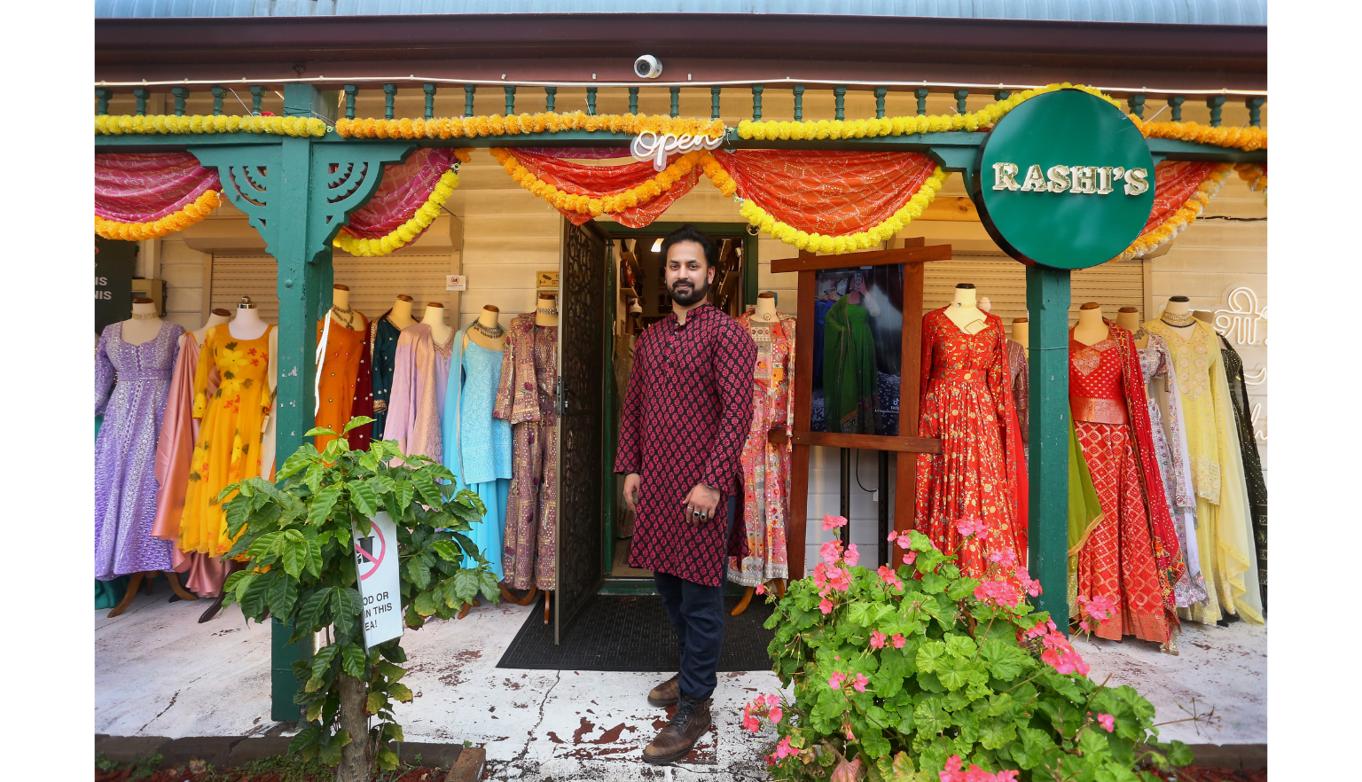 Man standing outside a fashion boutique with colourful dresses out the front