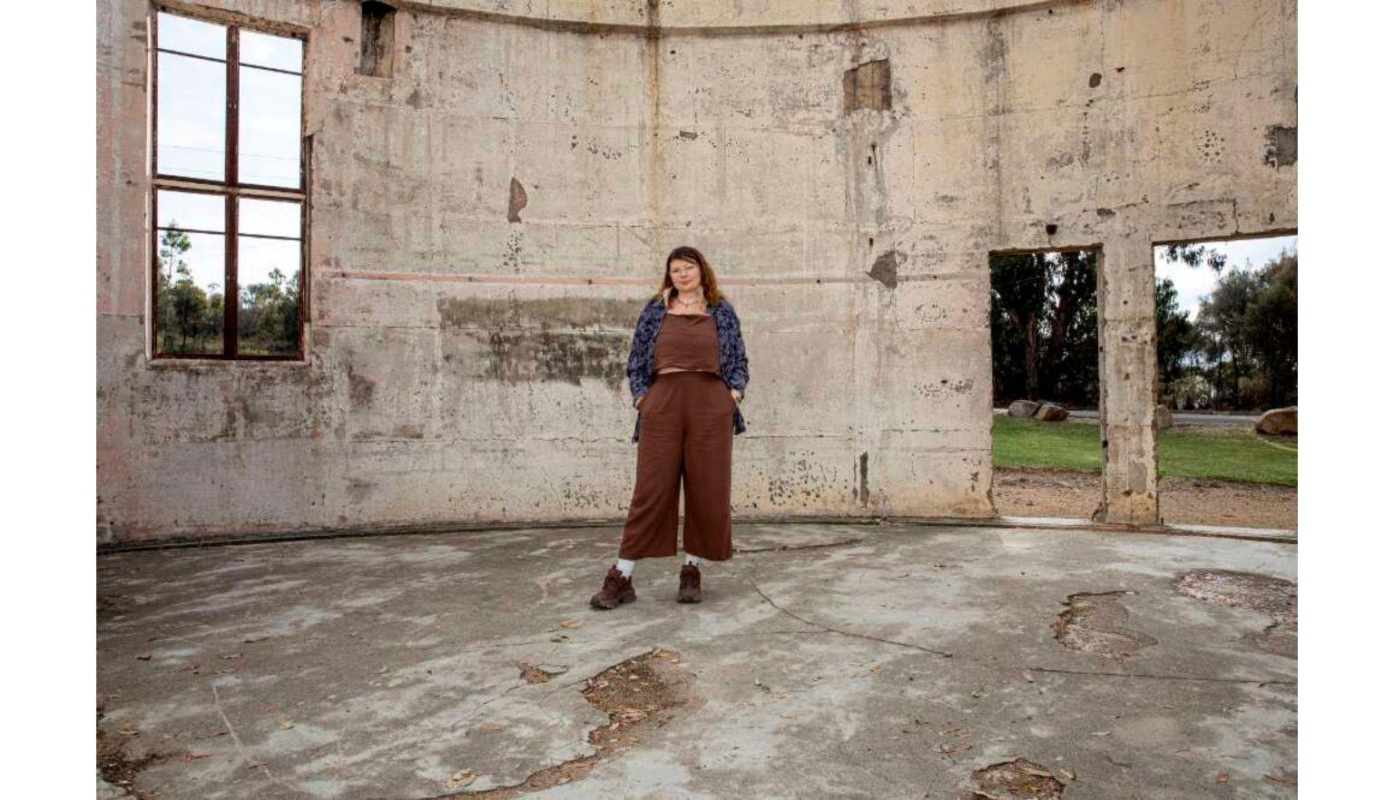 Karlie Noon standing in the burnt remains of a telescope at Mount Stromlo Observatory