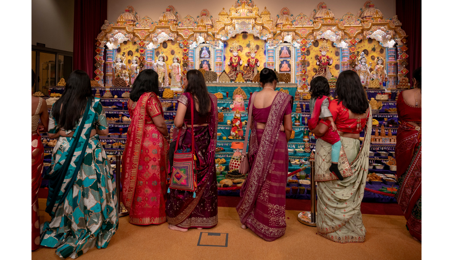 Women in colourful dress standing in front of a display of food