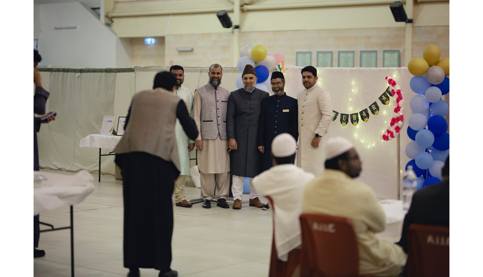 Five men posing for a photo in front of a white curtain
