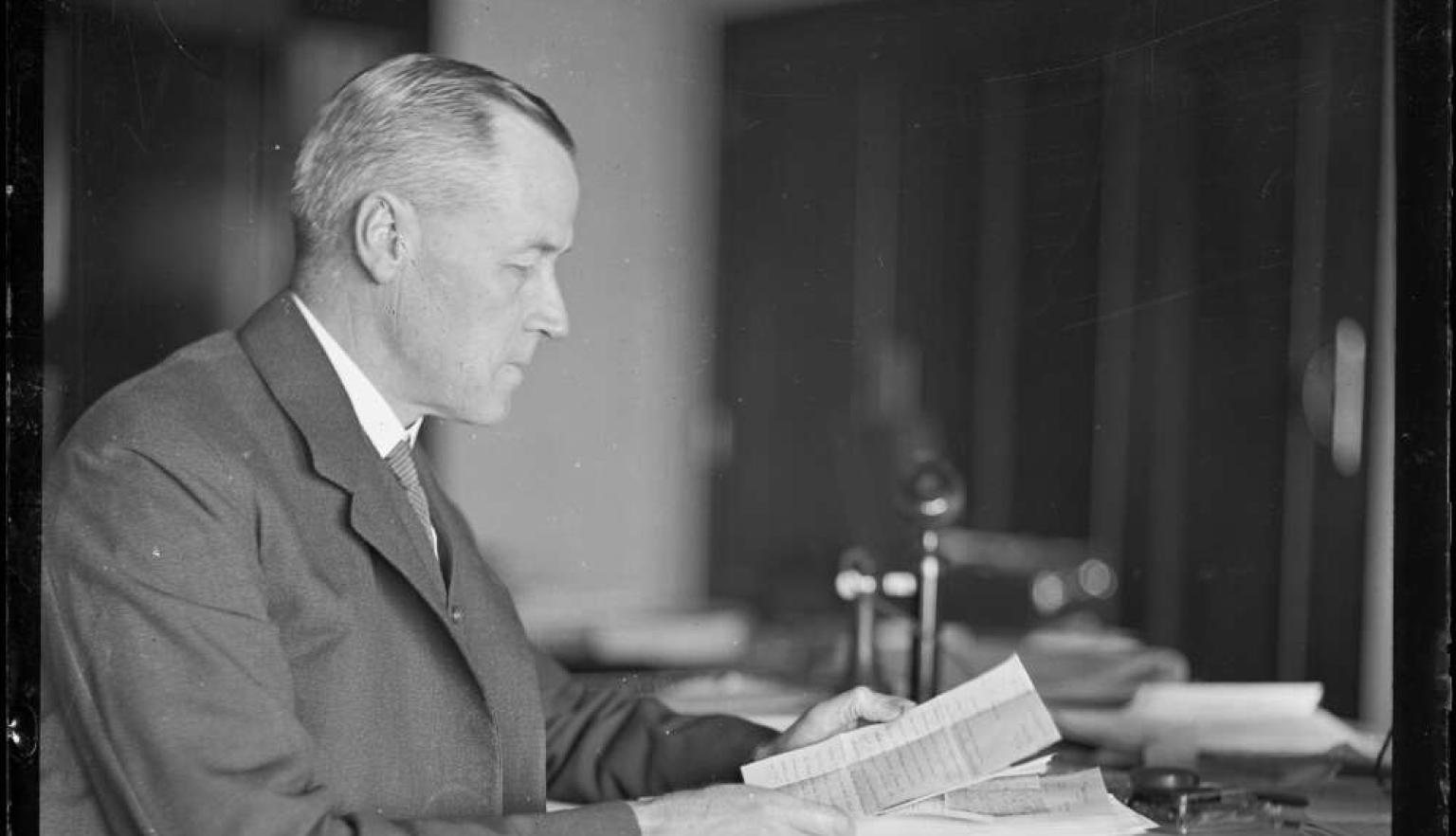 A man in a suit at his office table working