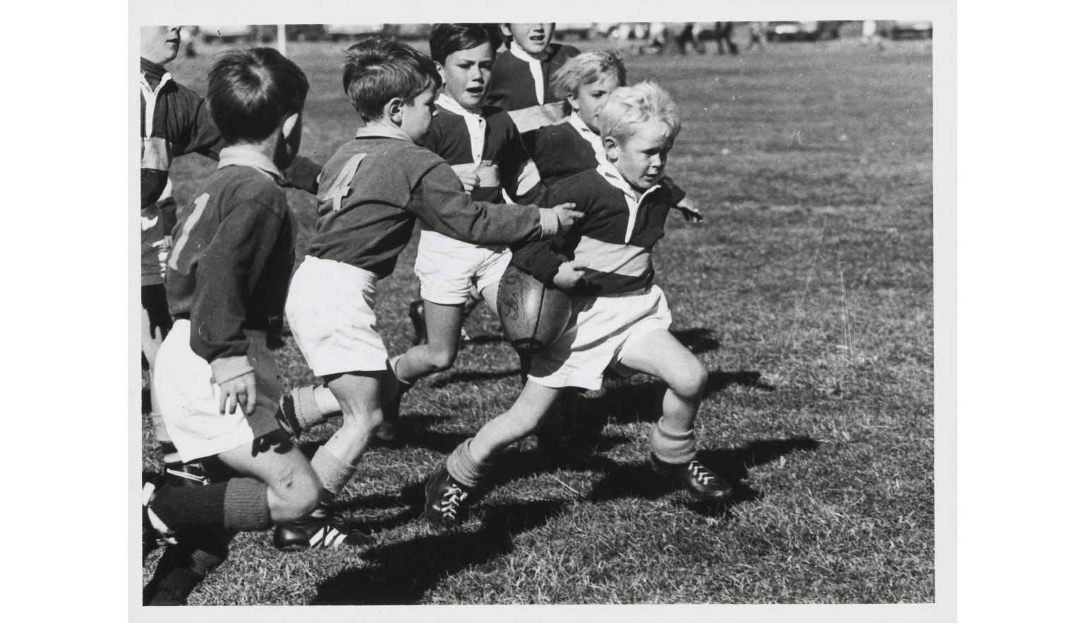 A black and white photograph of children playing rugby